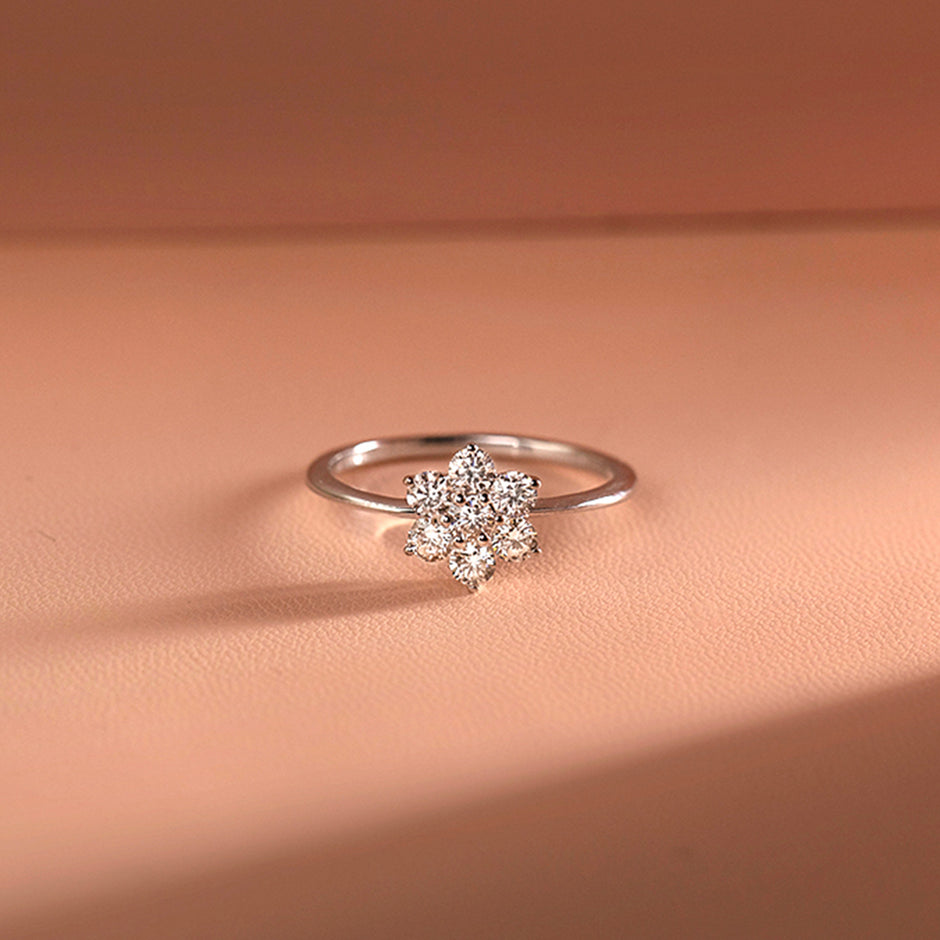 White Gold Engagement Diamond Ring with a diamond flower setting on a peach-colored fabric background