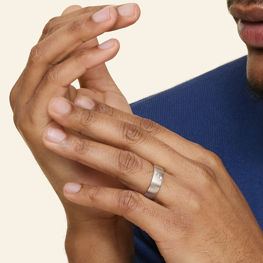 Close-up of two hands with a silver men diamond ring on a neutral background