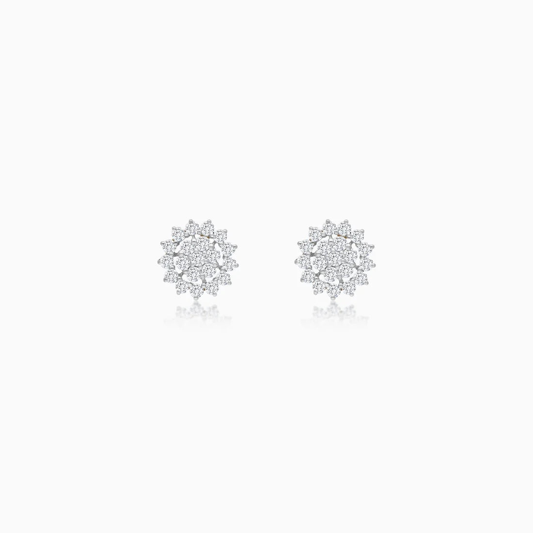 A pair of white  stud earrings with intricate, multi-layered snowflake or starburst designs set with clear diamonds, displayed on a clean white background with a soft reflection below.